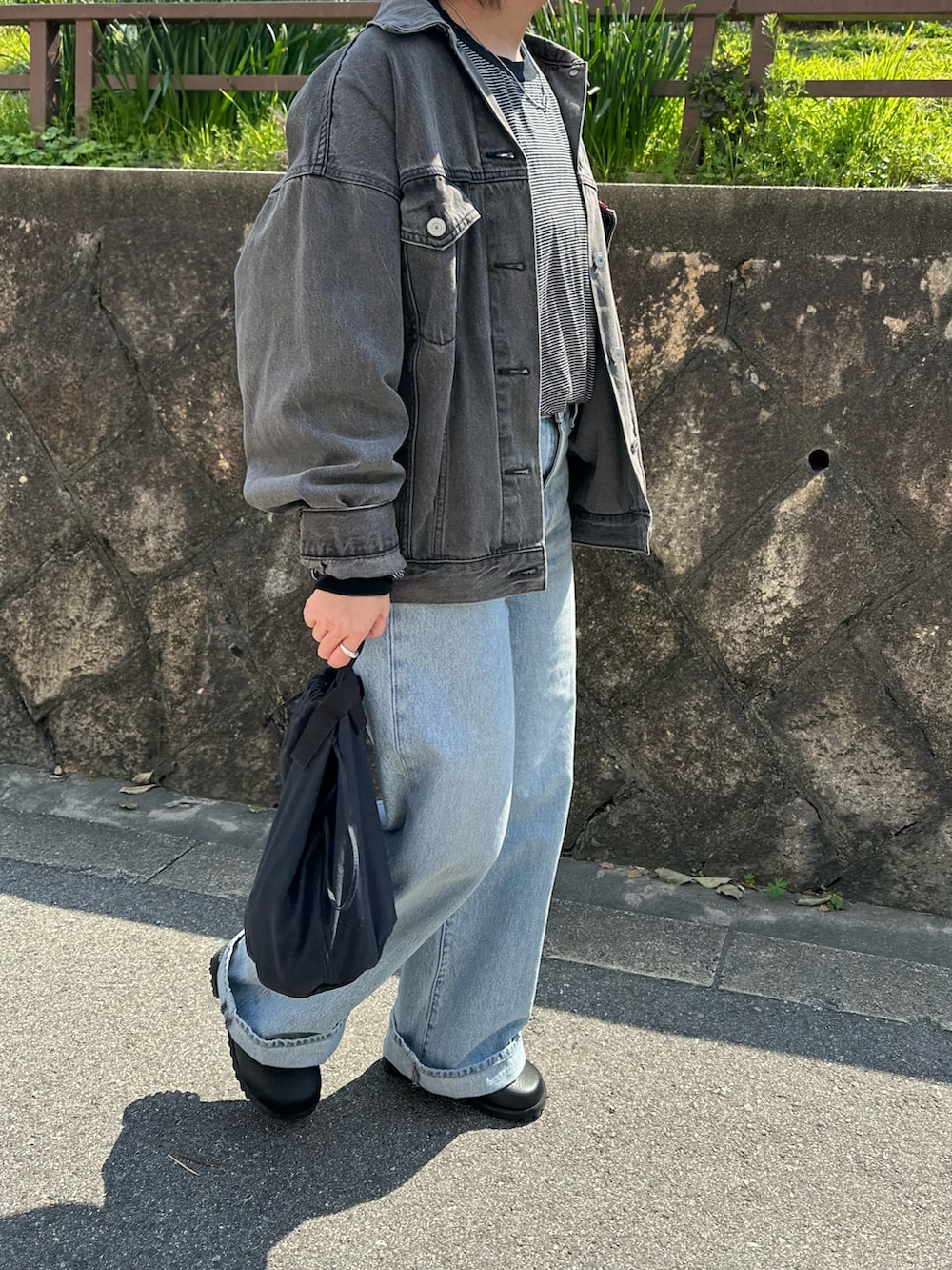 ブラック系のデニムジャケット、ブルー系のデニムパンツ、ブルー系のハンドバッグを着用したレディースの春コーディネートの4枚目の写真