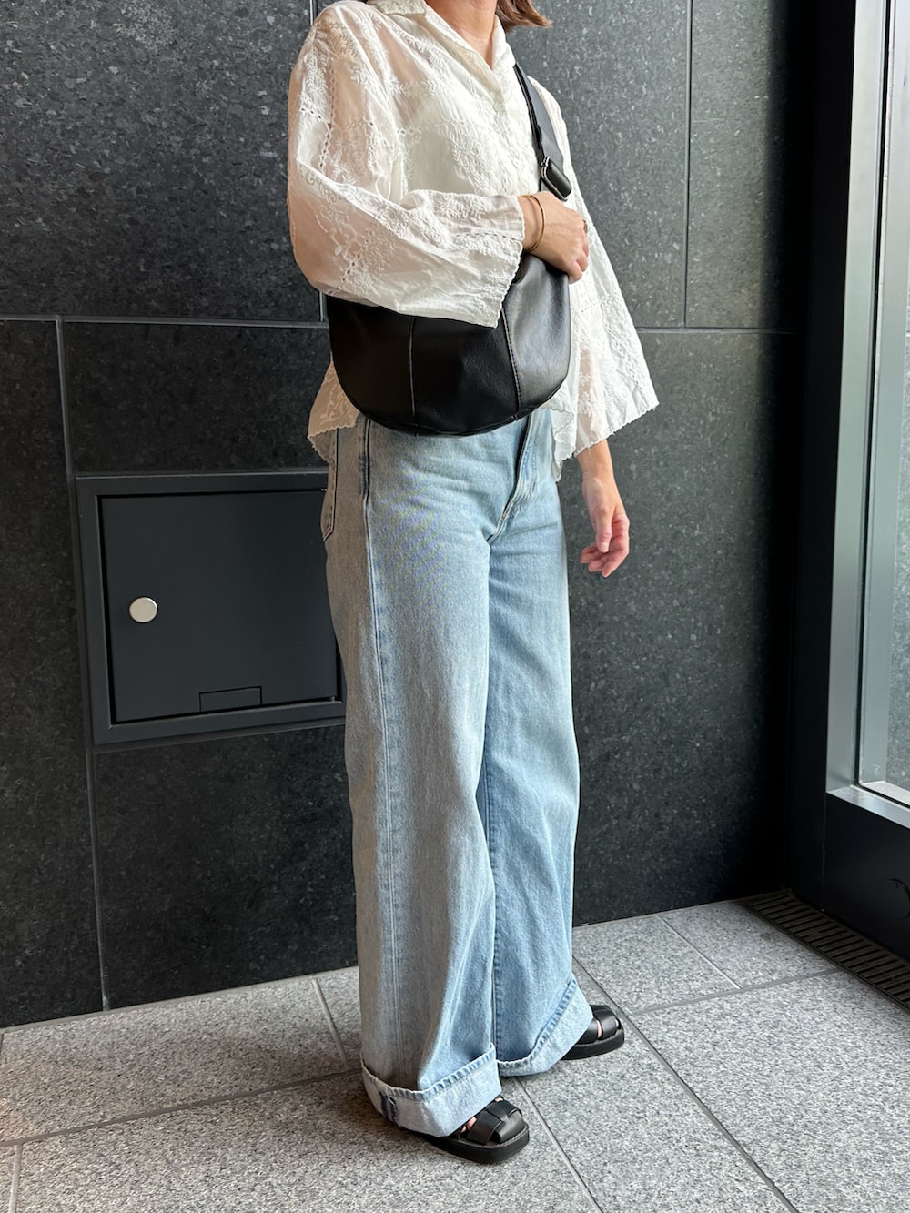 ブルー系のデニムパンツ、ブラック系のサンダル、ホワイト系のシャツ/ブラウスを着用したレディースの夏コーディネートの2枚目の写真