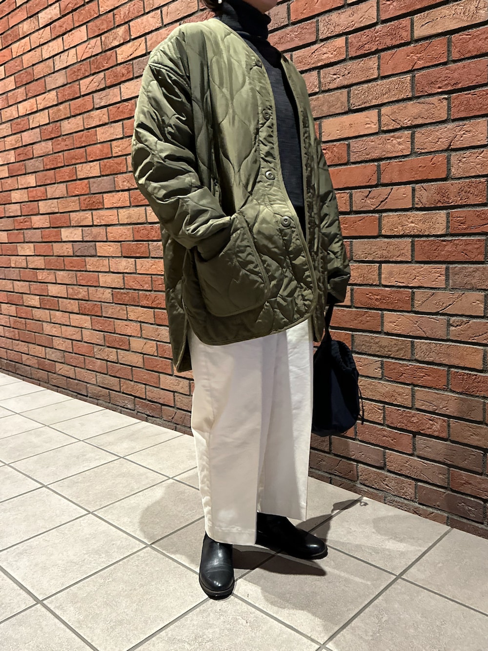 グリーン系のノーカラージャケット、ブルー系のハンドバッグ、ホワイト系のパンツを着用したレディースの秋コーディネートの2枚目の写真