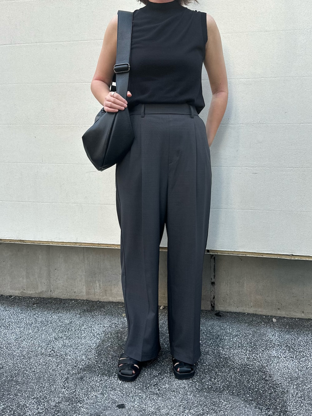 グレー系のスラックス、ブラック系のサンダル、ブラック系のトップスを着用したレディースの夏コーディネートの3枚目の写真