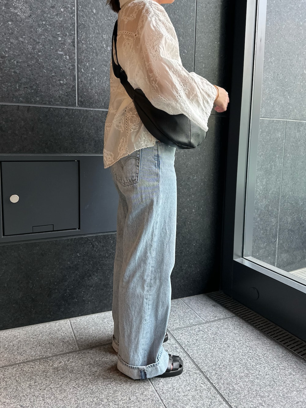 ブルー系のデニムパンツ、ブラック系のサンダル、ホワイト系のシャツ/ブラウスを着用したレディースの夏コーディネートの3枚目の写真