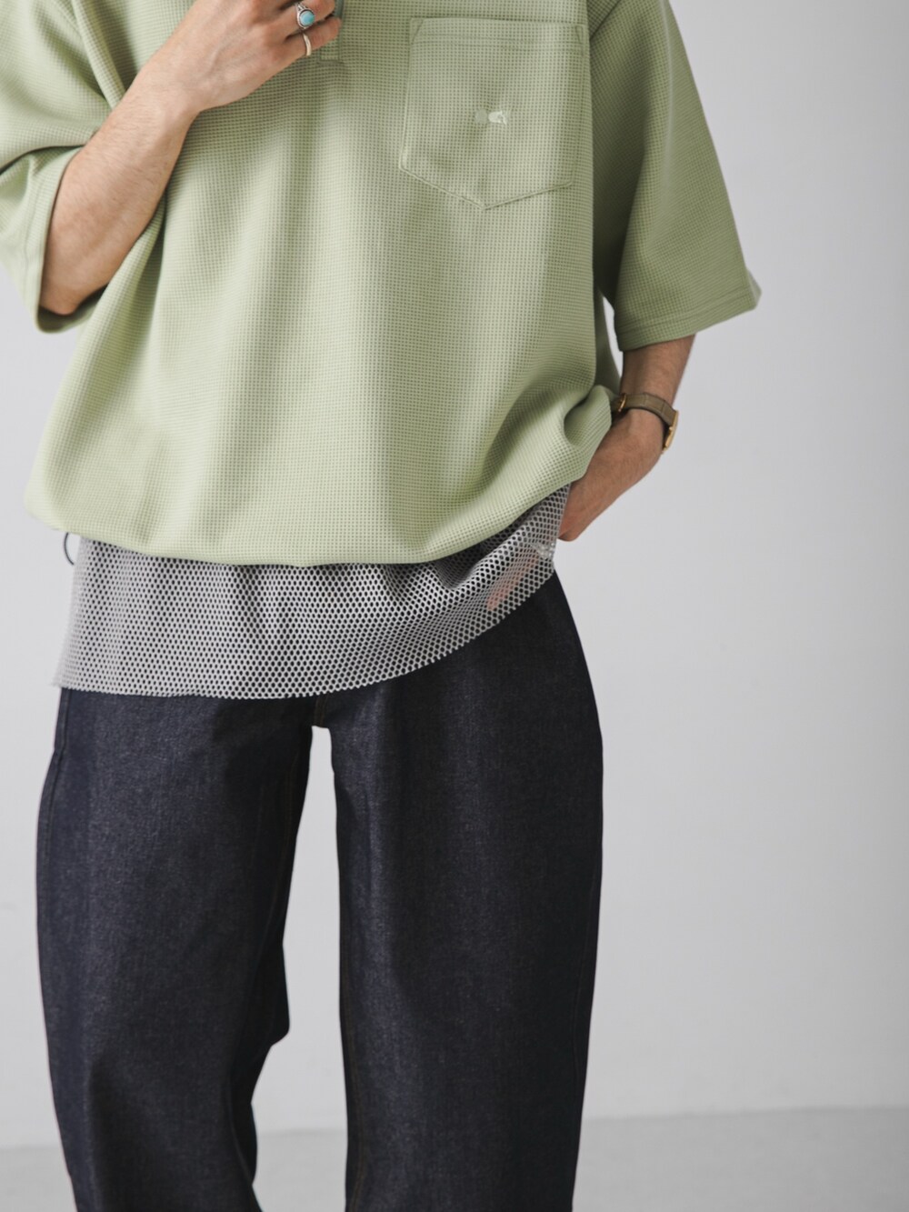 グリーン系のTシャツ/カットソー、グレー系のタンクトップ、ブルー系のデニムパンツを着用したメンズの夏コーディネートの4枚目の写真