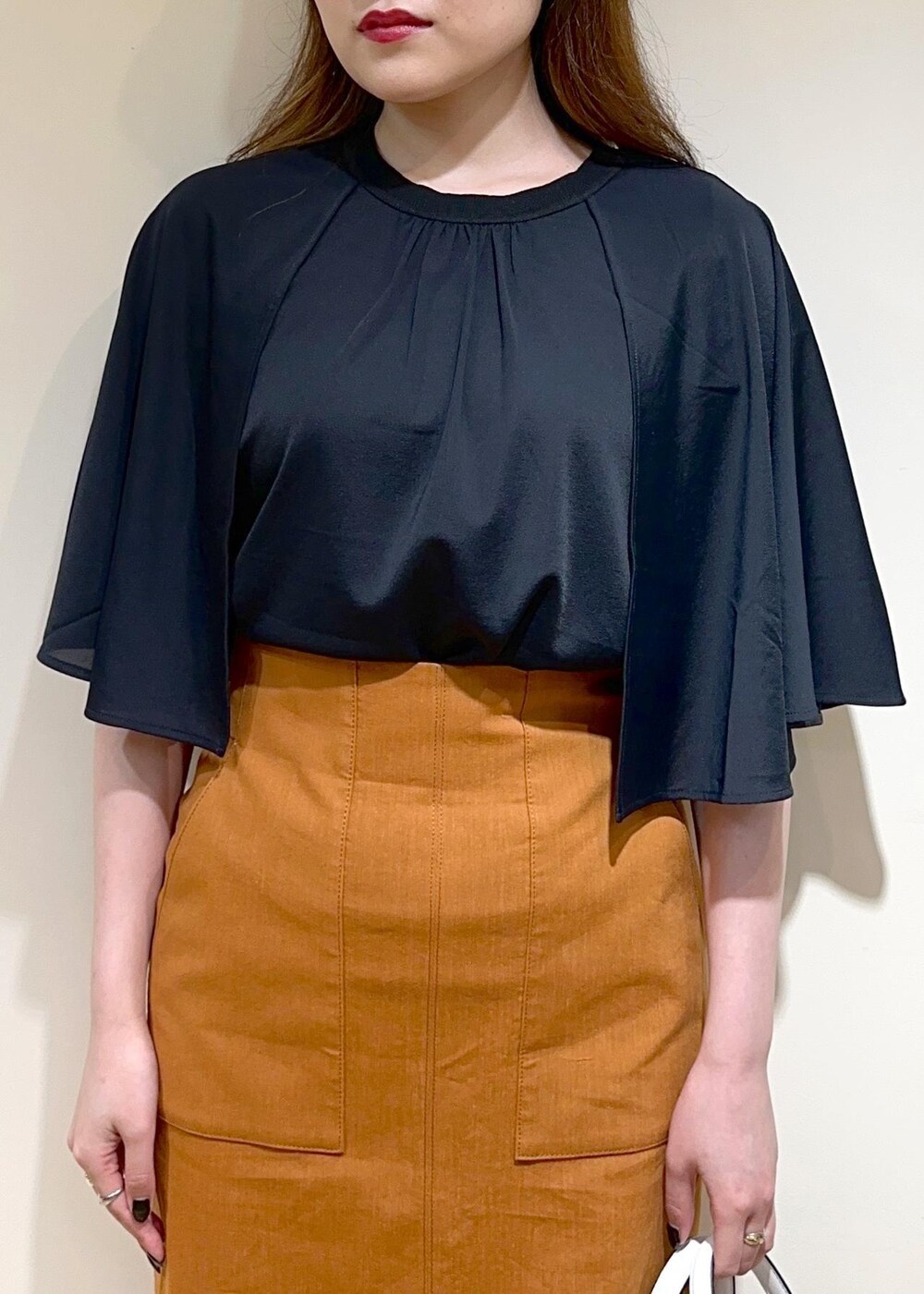 オレンジ系のスカート、ホワイト系のショルダーバッグ、ブラック系のパンプスを着用したレディースの夏コーディネートの4枚目の写真