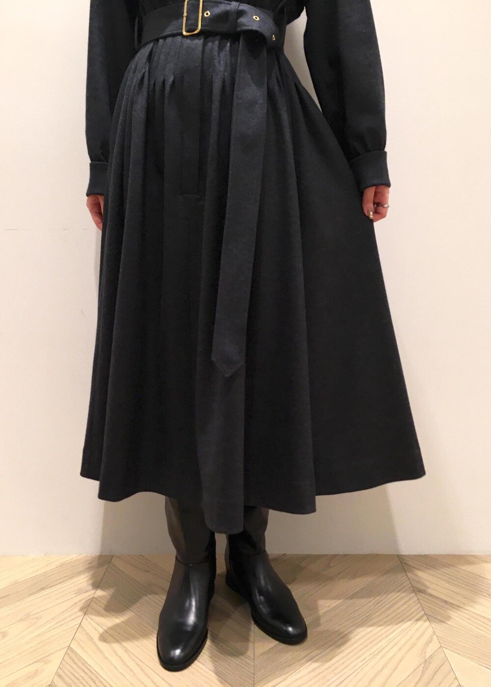 ホワイト系のハンドバッグ、ブラック系のブーツ、グレー系のワンピースを着用したレディースの冬コーディネートの7枚目の写真