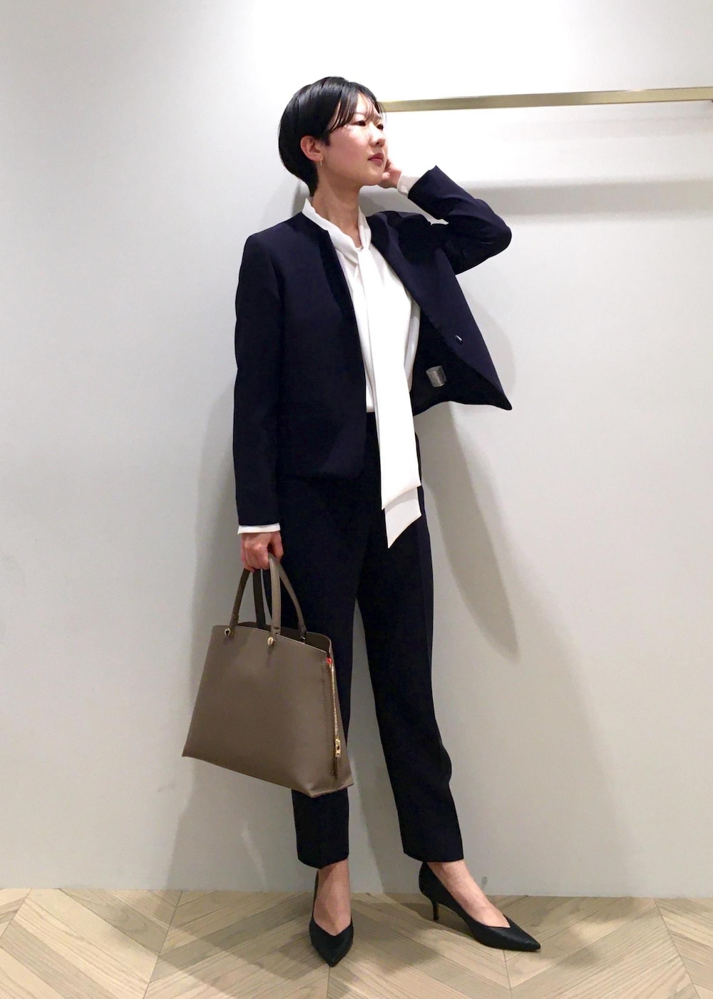 ブラック系のパンプス、ブラウン系のハンドバッグ、ブルー系のノーカラージャケットを着用したレディースの冬コーディネートの3枚目の写真