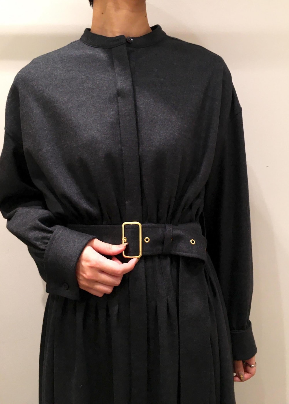 ホワイト系のハンドバッグ、ブラック系のブーツ、グレー系のワンピースを着用したレディースの冬コーディネートの4枚目の写真