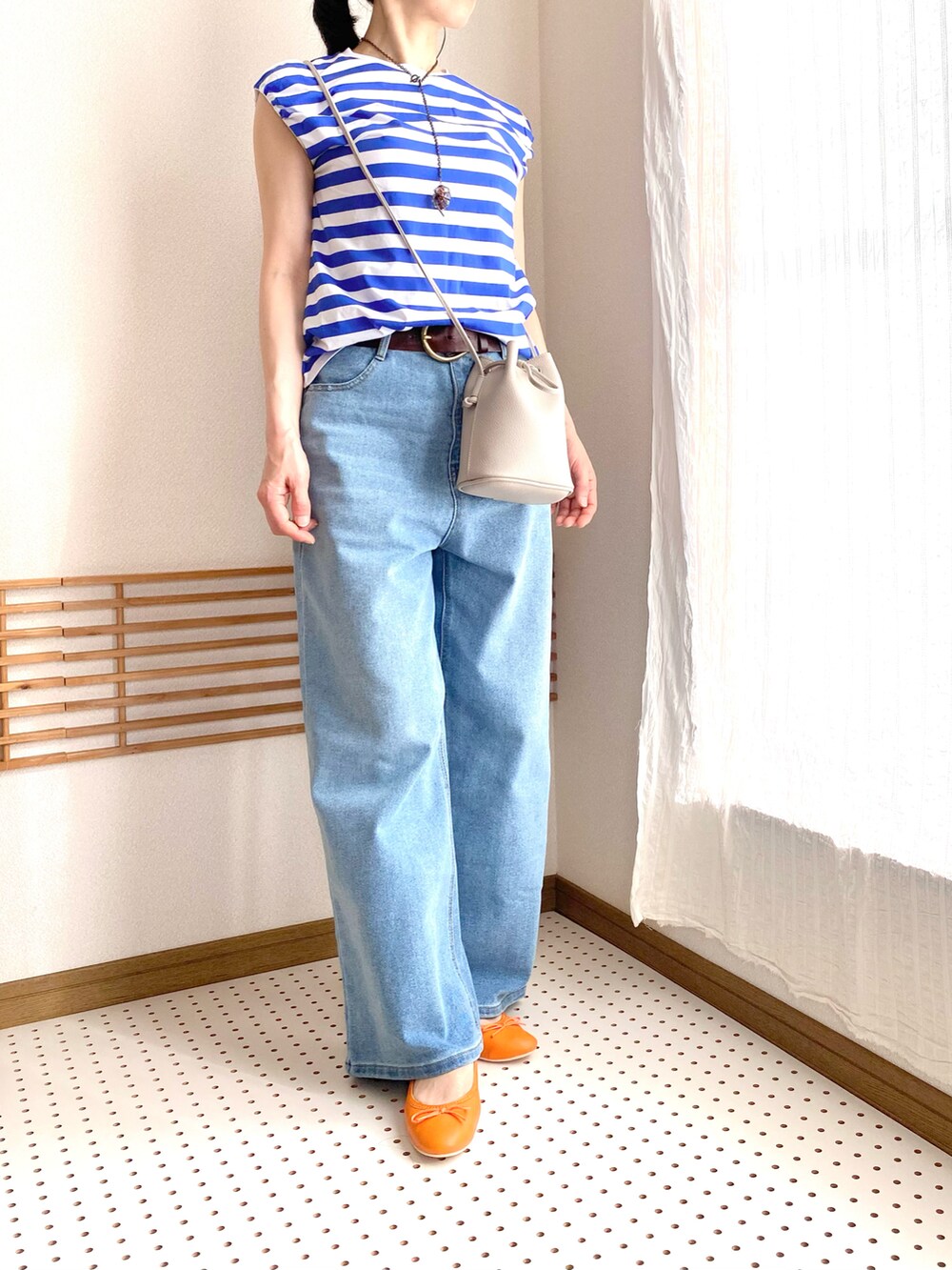 ブルー系のデニムパンツ、ブラック系のバレエシューズ、ブルー系のTシャツ/カットソーを着用したレディースの夏コーディネートの2枚目の写真