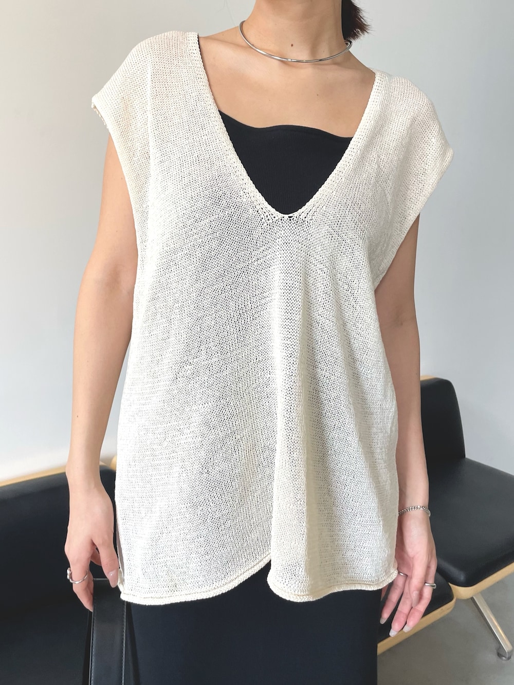 ホワイト系のベスト、ブラック系のワンピースを着用したレディースの春コーディネートの2枚目の写真