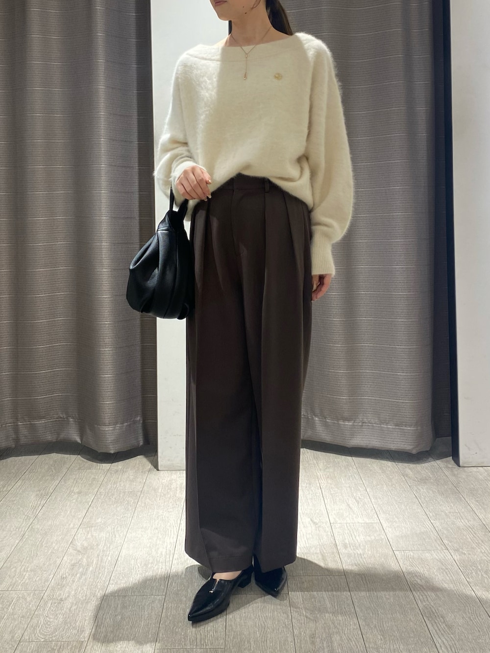 ホワイト系のニット/セーター、ブラック系のハンドバッグ、ブラウン系のその他パンツを着用したレディースの夏コーディネートの2枚目の写真