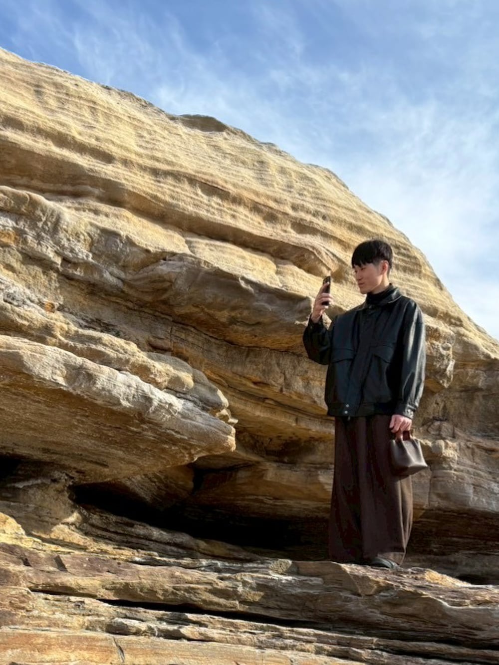 ブラック系のブルゾン、ブラック系のスニーカー、ブラウン系のスラックスを着用したメンズの春コーディネートの2枚目の写真