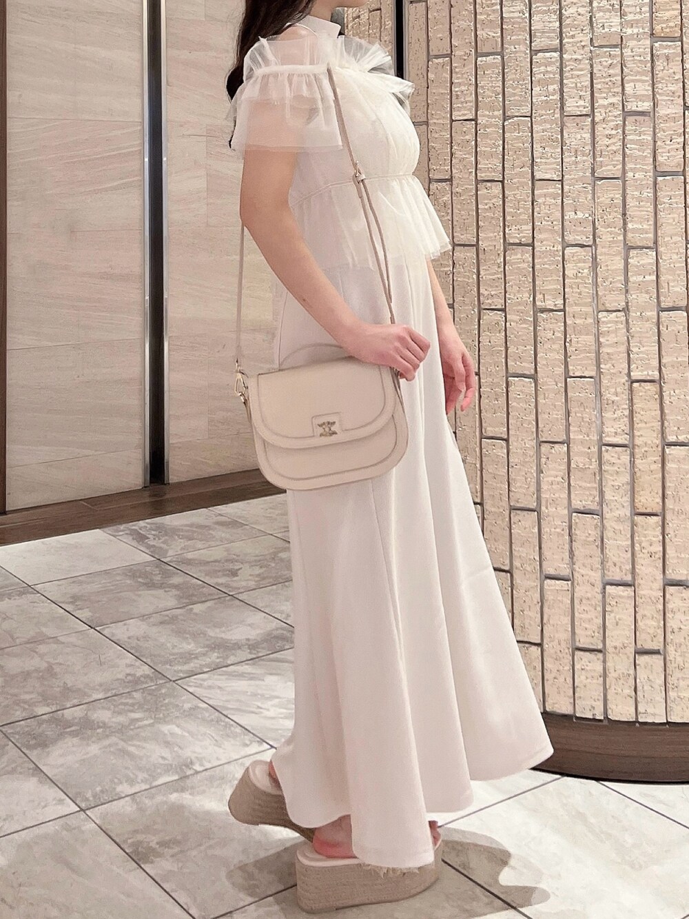 ホワイト系のワンピース、ホワイト系のハンドバッグ、オレンジ系のサンダルを着用したレディースの夏コーディネートの3枚目の写真