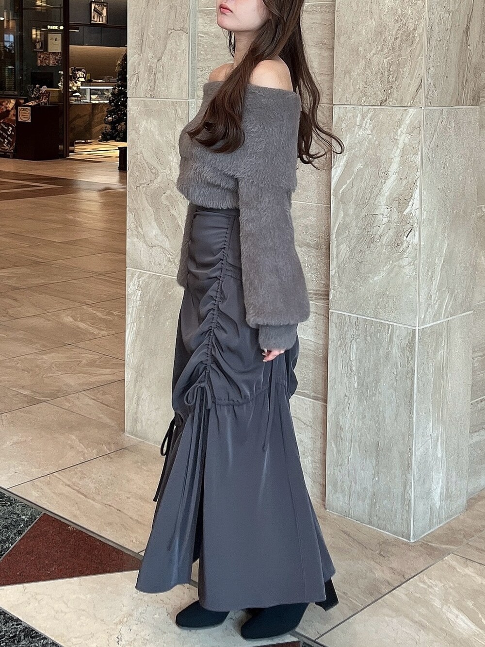 ブラウン系のニット/セーター、グレー系のスカート、その他のブーツを着用したレディースの冬コーディネートの5枚目の写真