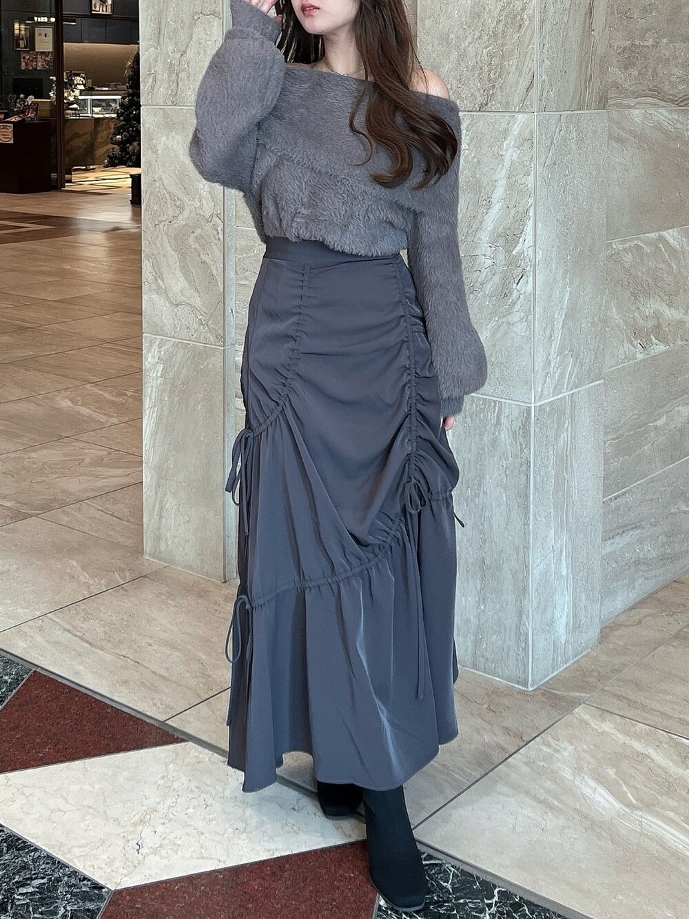 ブラウン系のニット/セーター、グレー系のスカート、その他のブーツを着用したレディースの冬コーディネートの3枚目の写真