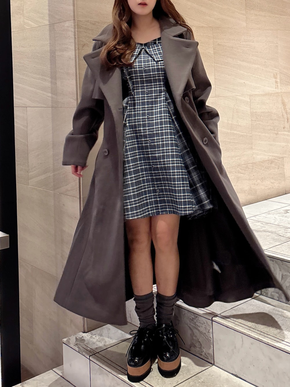 ブラウン系のトレンチコート、ブルー系のワンピース、その他のローファーを着用したレディースの秋コーディネートの4枚目の写真