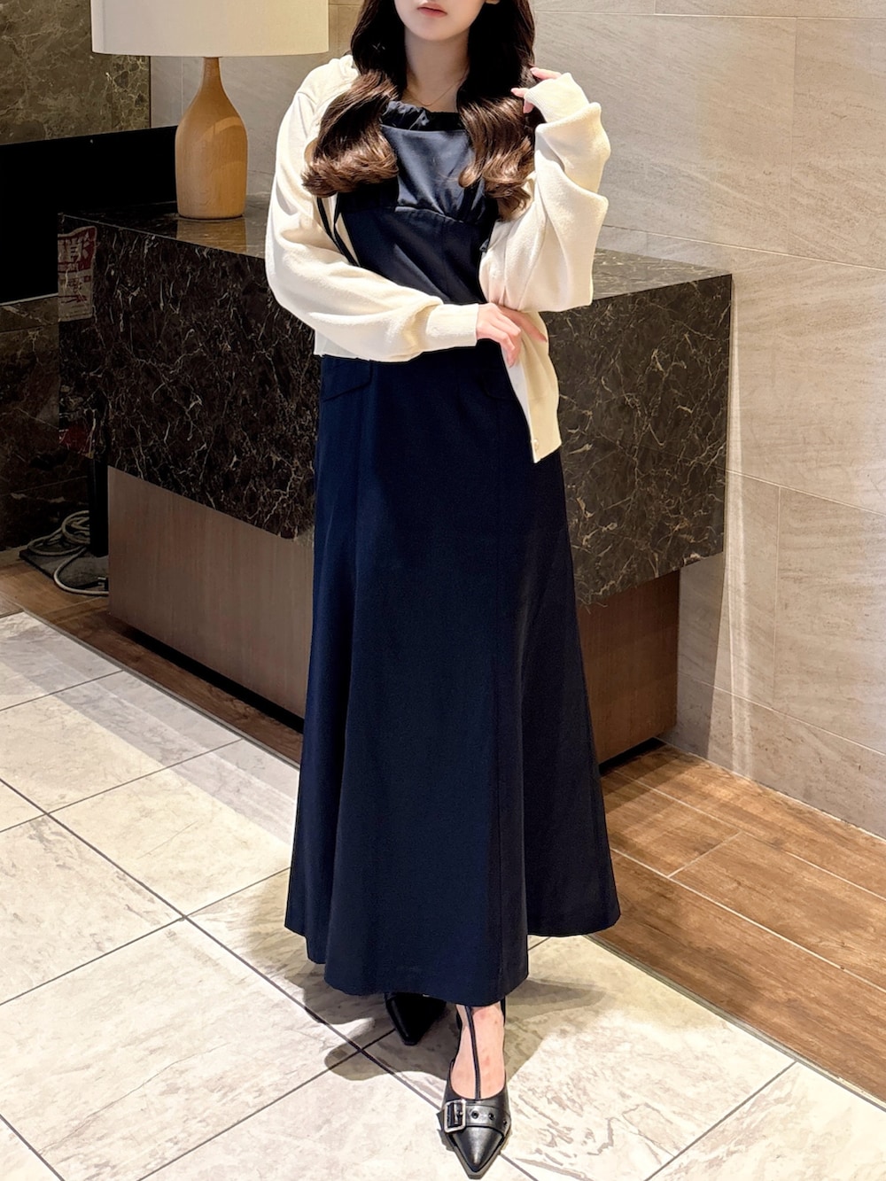 ブルー系のワンピース、ホワイト系のカーディガン/ボレロ、ブラック系のパンプスを着用したレディースの秋コーディネートの2枚目の写真