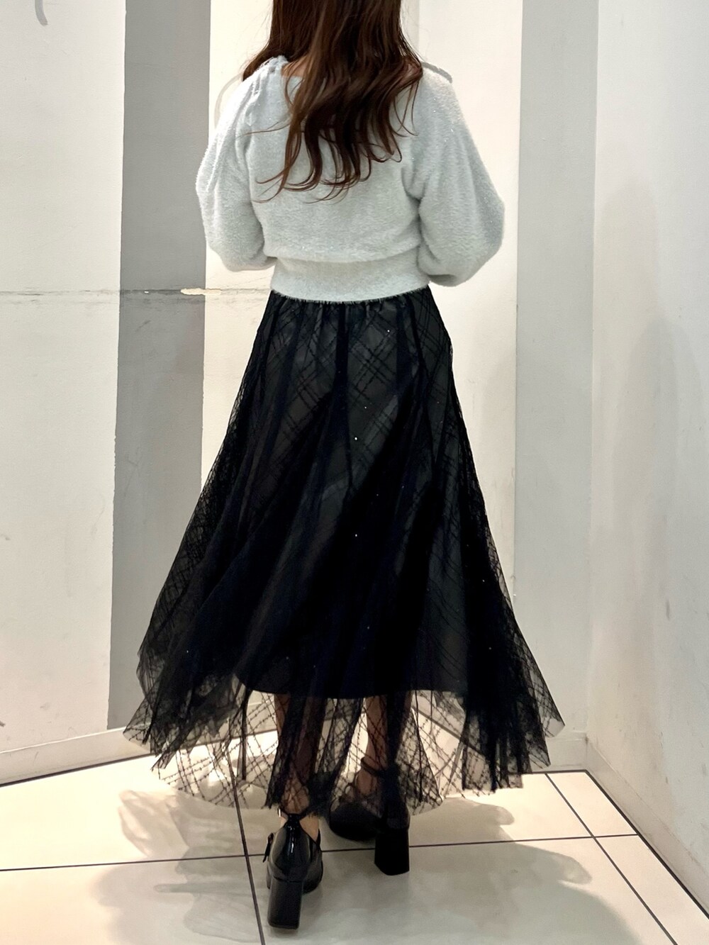 グレー系のカーディガン/ボレロ、グレー系のキャミソール、ブラック系のスカートを着用したレディースの冬コーディネートの3枚目の写真