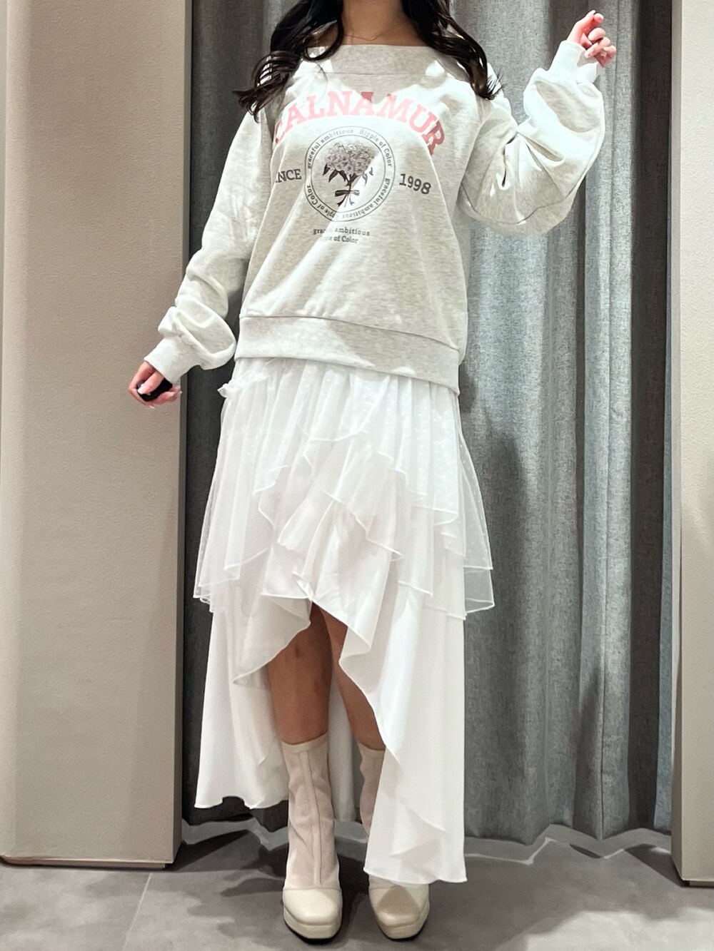 グレー系のスウェット、ホワイト系のスカート、ホワイト系のブーツを着用したレディースの春コーディネートの2枚目の写真