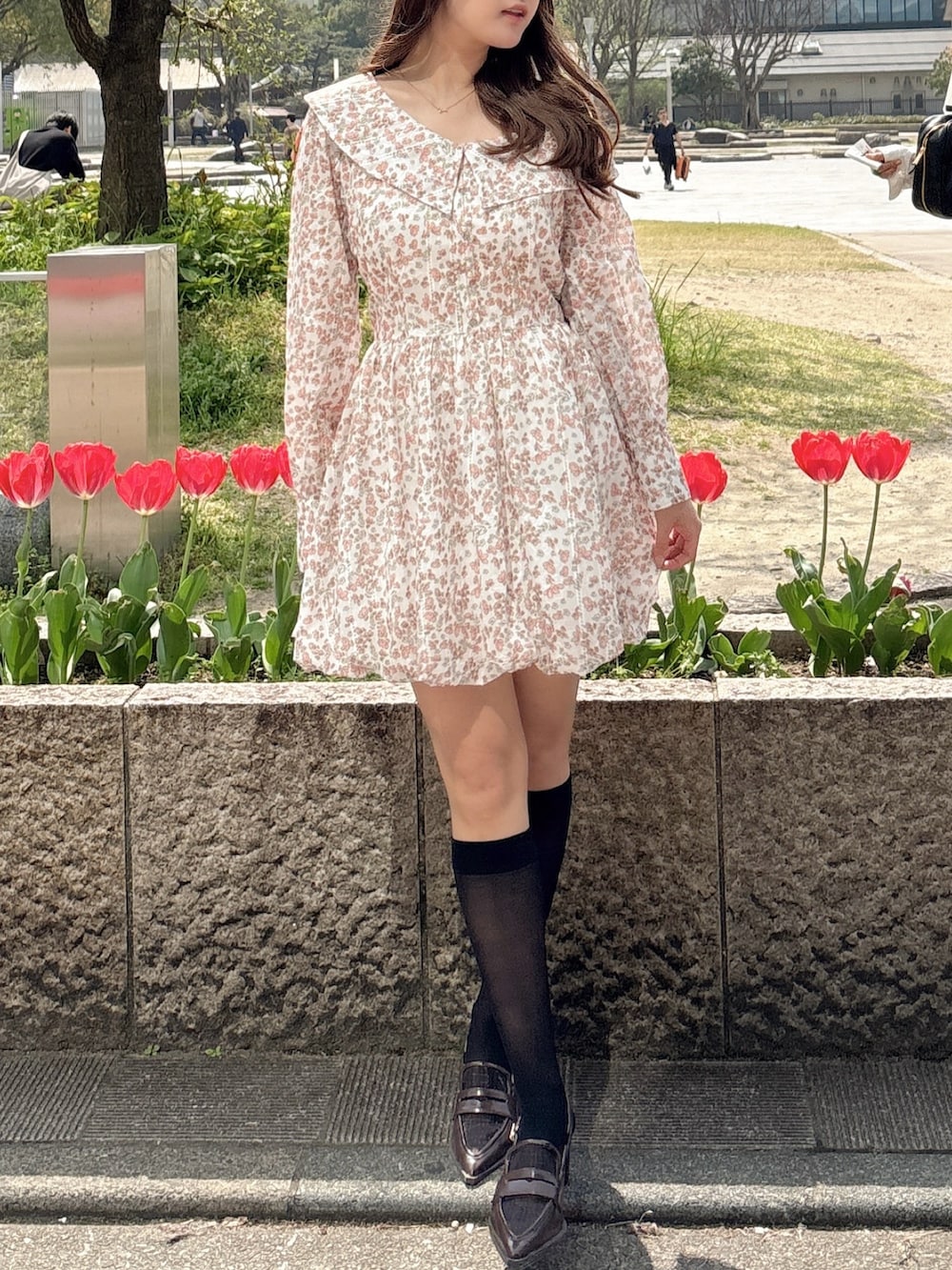 オレンジ系のワンピース、ブラウン系のローファーを着用したレディースの春コーディネートの3枚目の写真