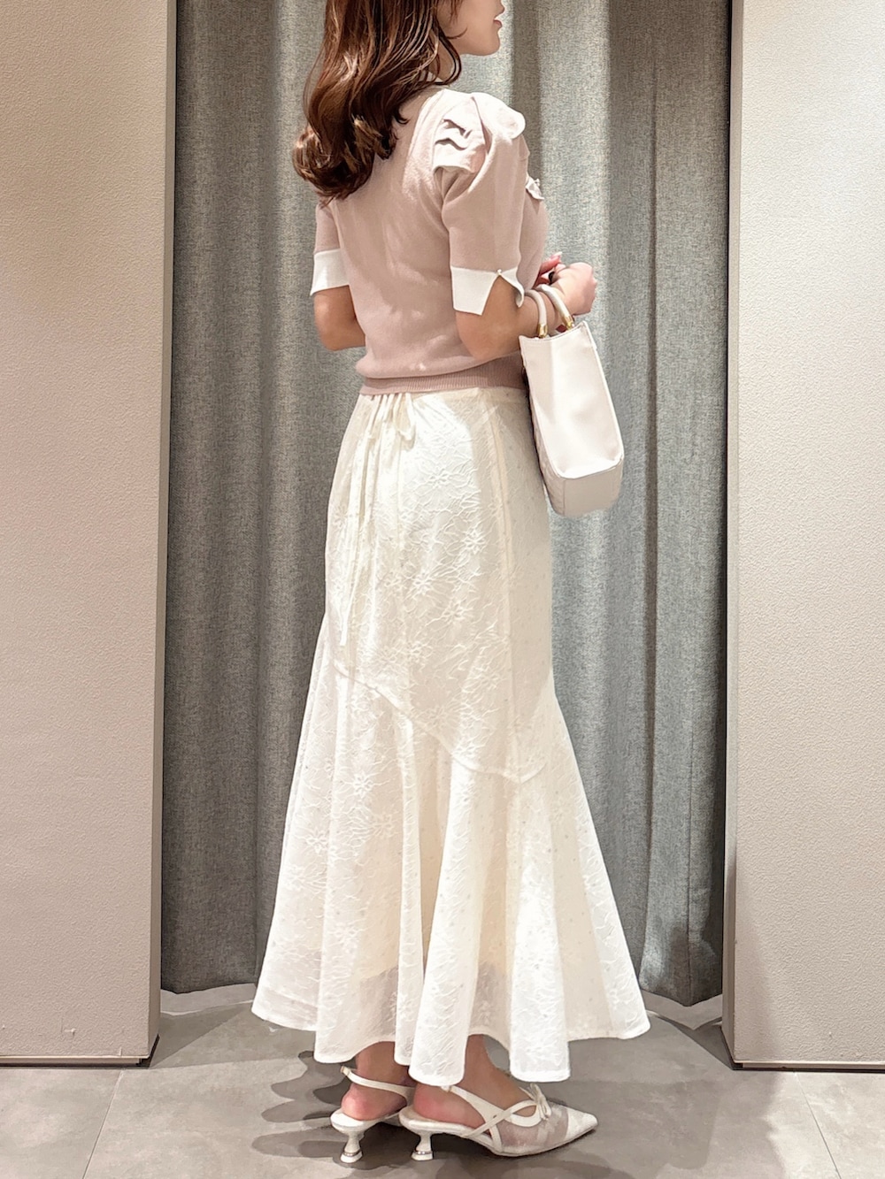 ピンク系のニット/セーター、ピンク系のハンドバッグ、ホワイト系のスカートを着用したレディースの春コーディネートの6枚目の写真