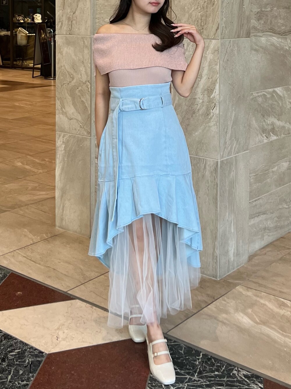 ピンク系のニット/セーター、ブルー系のスカート、ホワイト系のパンプスを着用したレディースの夏コーディネートの2枚目の写真