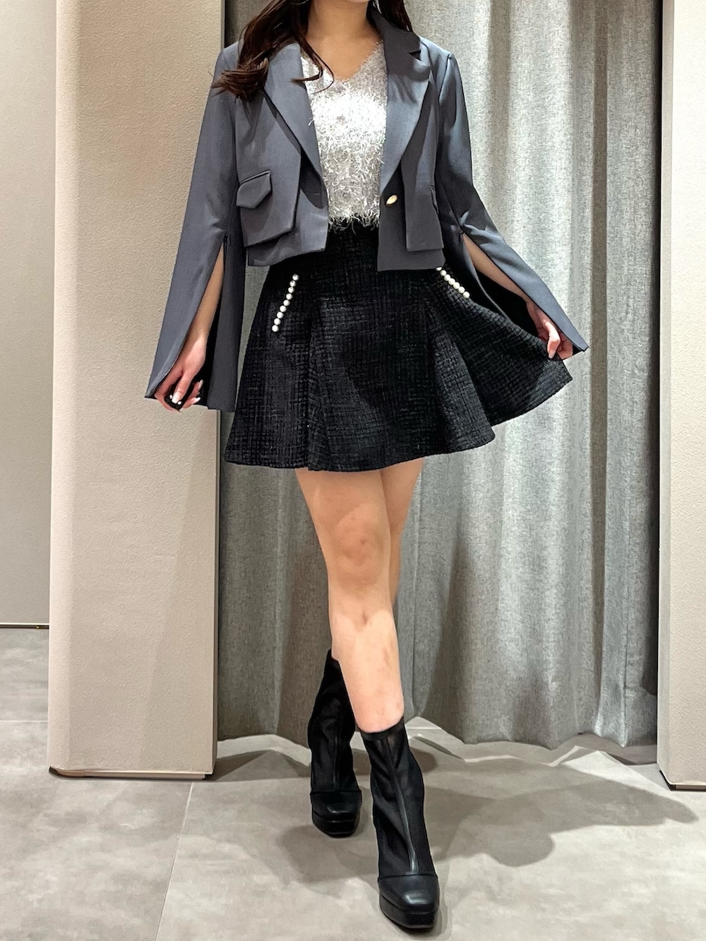 グレー系のテーラードジャケット、グレー系のニット/セーター、ブラック系のスカートを着用したレディースの春コーディネートの2枚目の写真