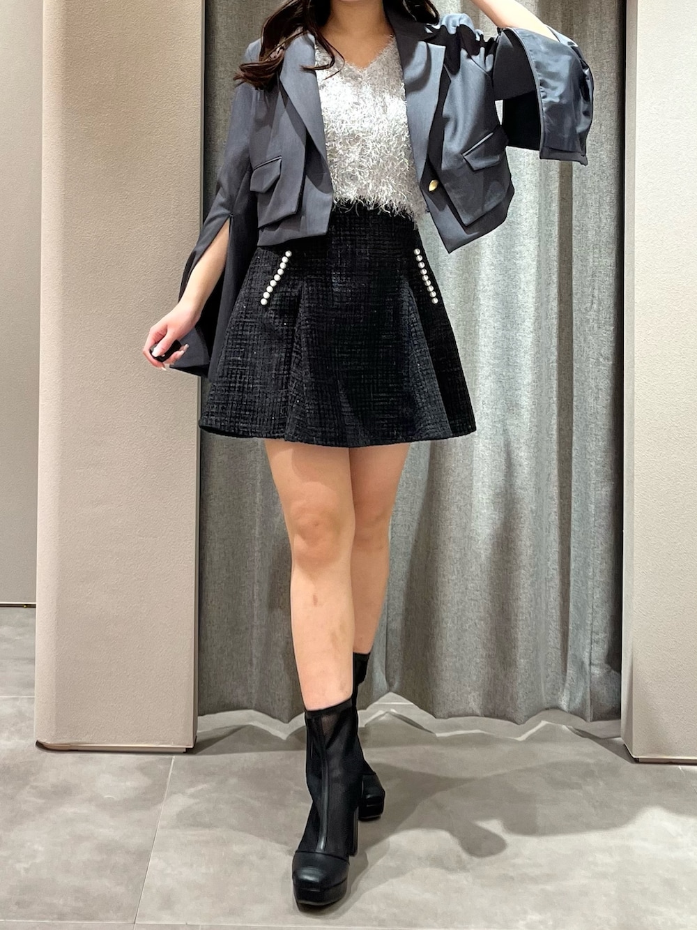 グレー系のテーラードジャケット、グレー系のニット/セーター、ブラック系のスカートを着用したレディースの春コーディネートの3枚目の写真