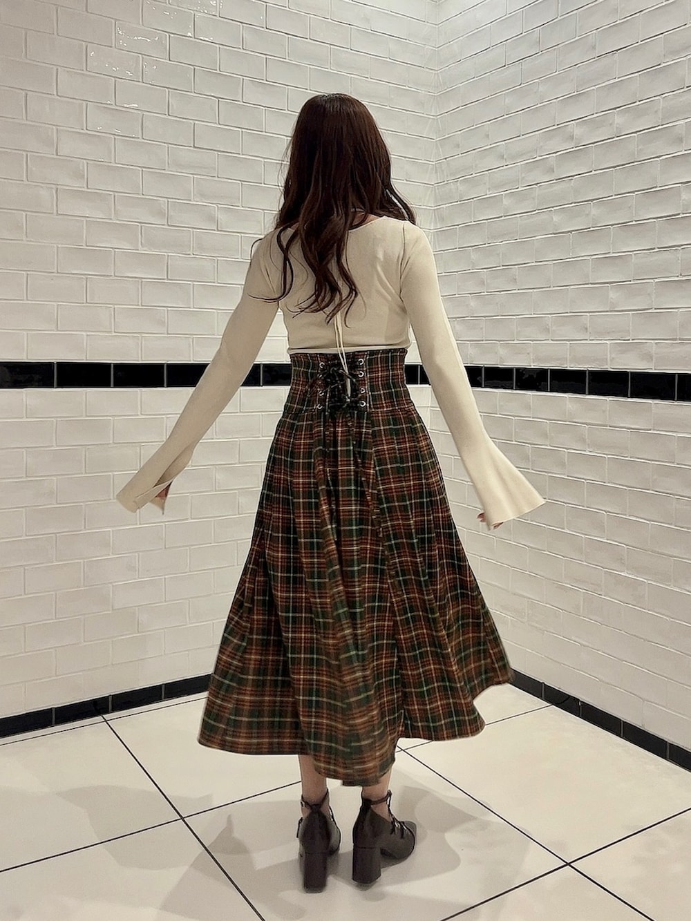 ホワイト系のニット/セーター、グリーン系のスカート、ブラウン系のパンプスを着用したレディースの冬コーディネートの3枚目の写真