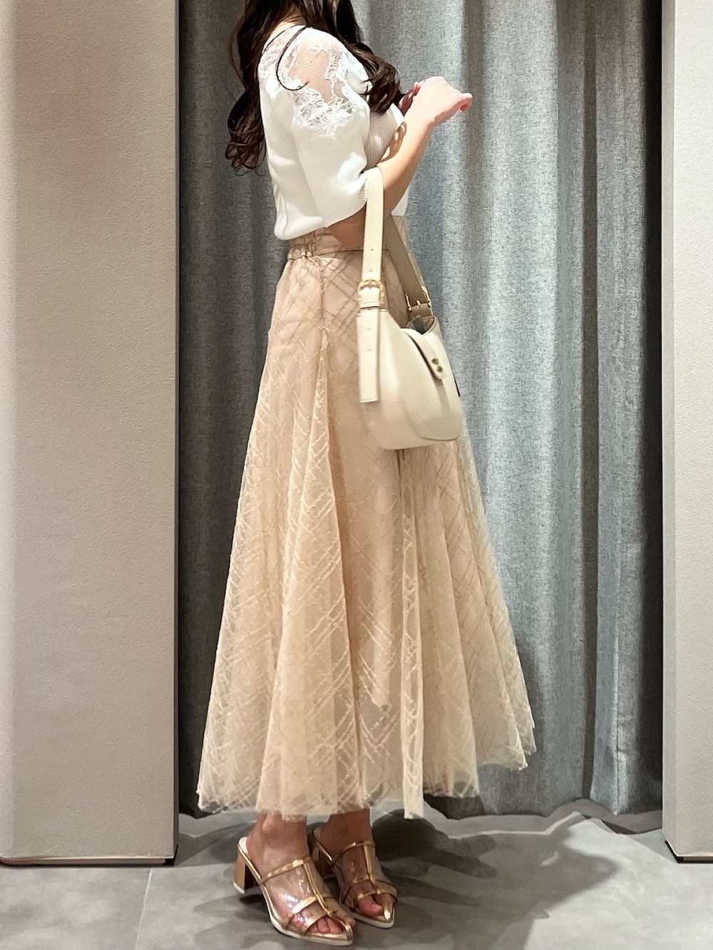 ホワイト系のニット/セーター、ベージュ系のスカート、ゴールド系のパンプスを着用したレディースの春コーディネートの6枚目の写真