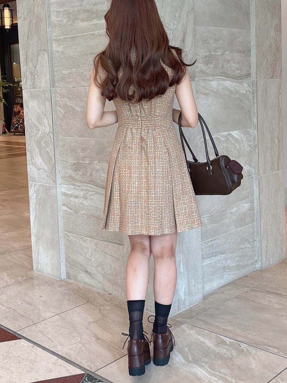 イエロー系のワンピース、ブラウン系のボストンバッグ、ブラウン系のローファーを着用したレディースの秋コーディネートの8枚目の写真