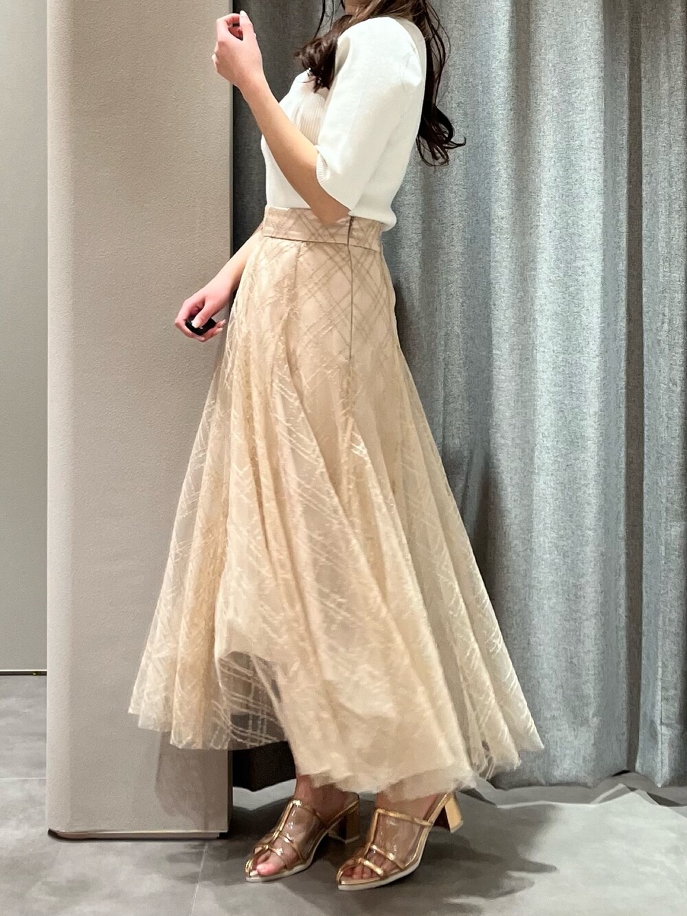 ホワイト系のニット/セーター、ベージュ系のスカート、ゴールド系のパンプスを着用したレディースの春コーディネートの5枚目の写真