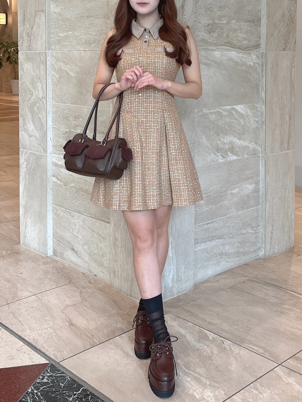 イエロー系のワンピース、ブラウン系のボストンバッグ、ブラウン系のローファーを着用したレディースの秋コーディネートの3枚目の写真