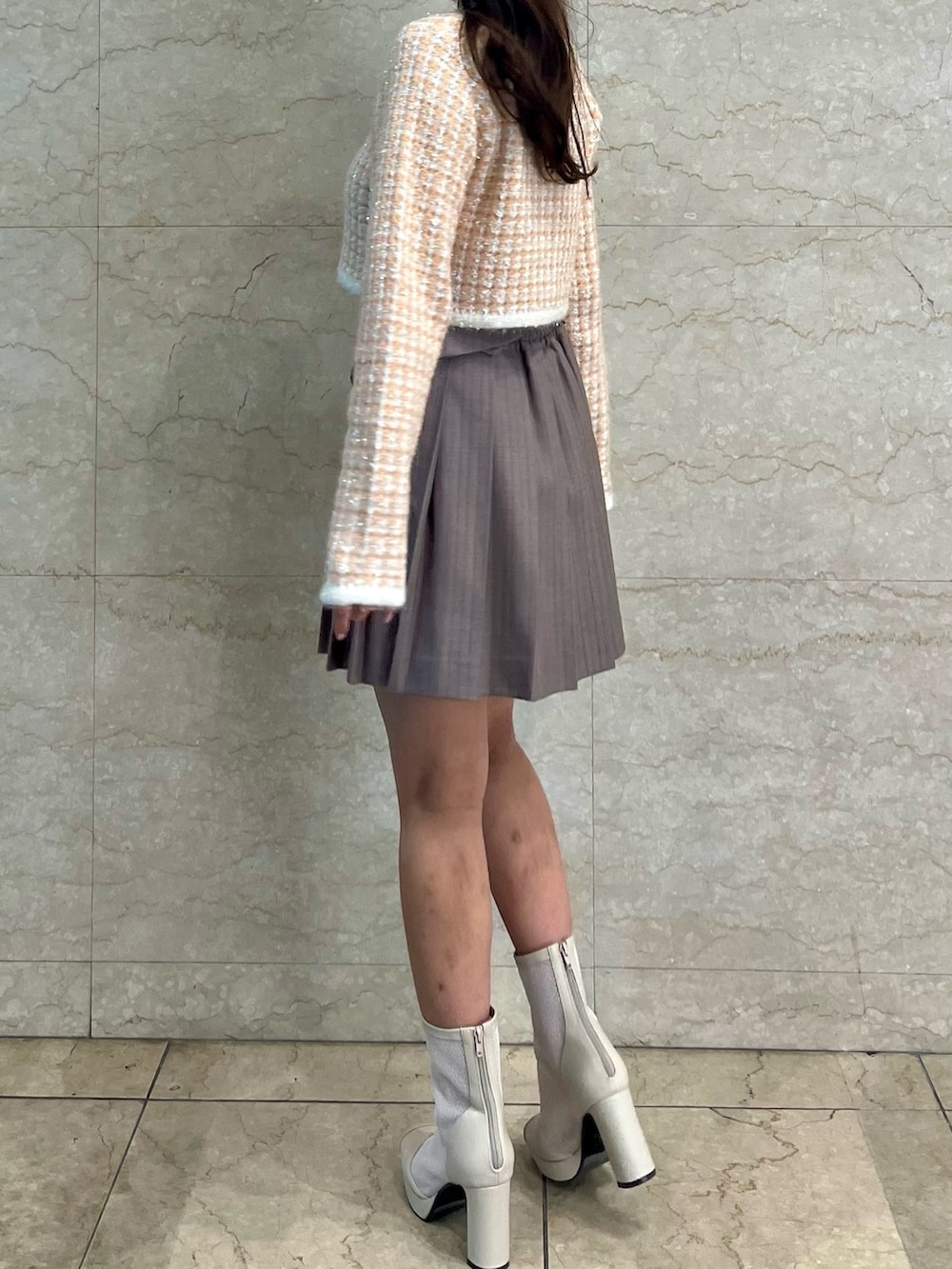 オレンジ系のノーカラージャケット、ベージュ系のスカート、ホワイト系のブーツを着用したレディースの冬コーディネートの5枚目の写真