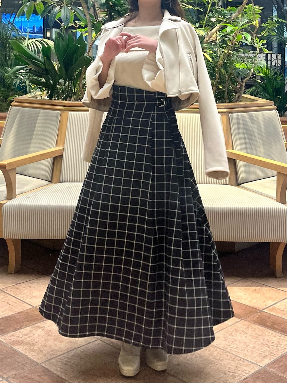 ホワイト系のライダースジャケット、ホワイト系のニット/セーター、ブラック系のスカートを着用したレディースの春コーディネートの3枚目の写真