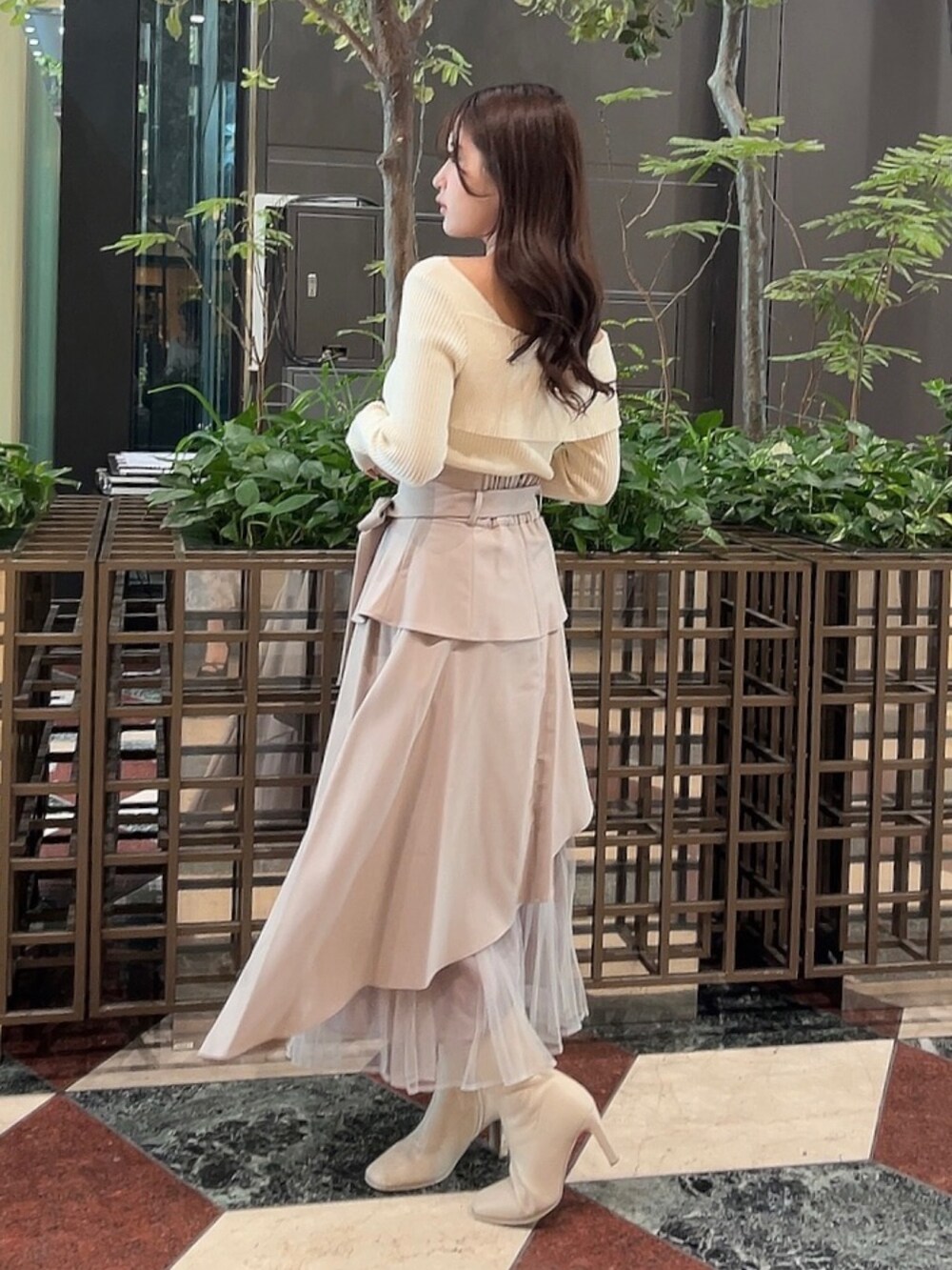 ホワイト系のニット/セーター、ベージュ系のスカート、ホワイト系のブーツを着用したレディースの冬コーディネートの2枚目の写真
