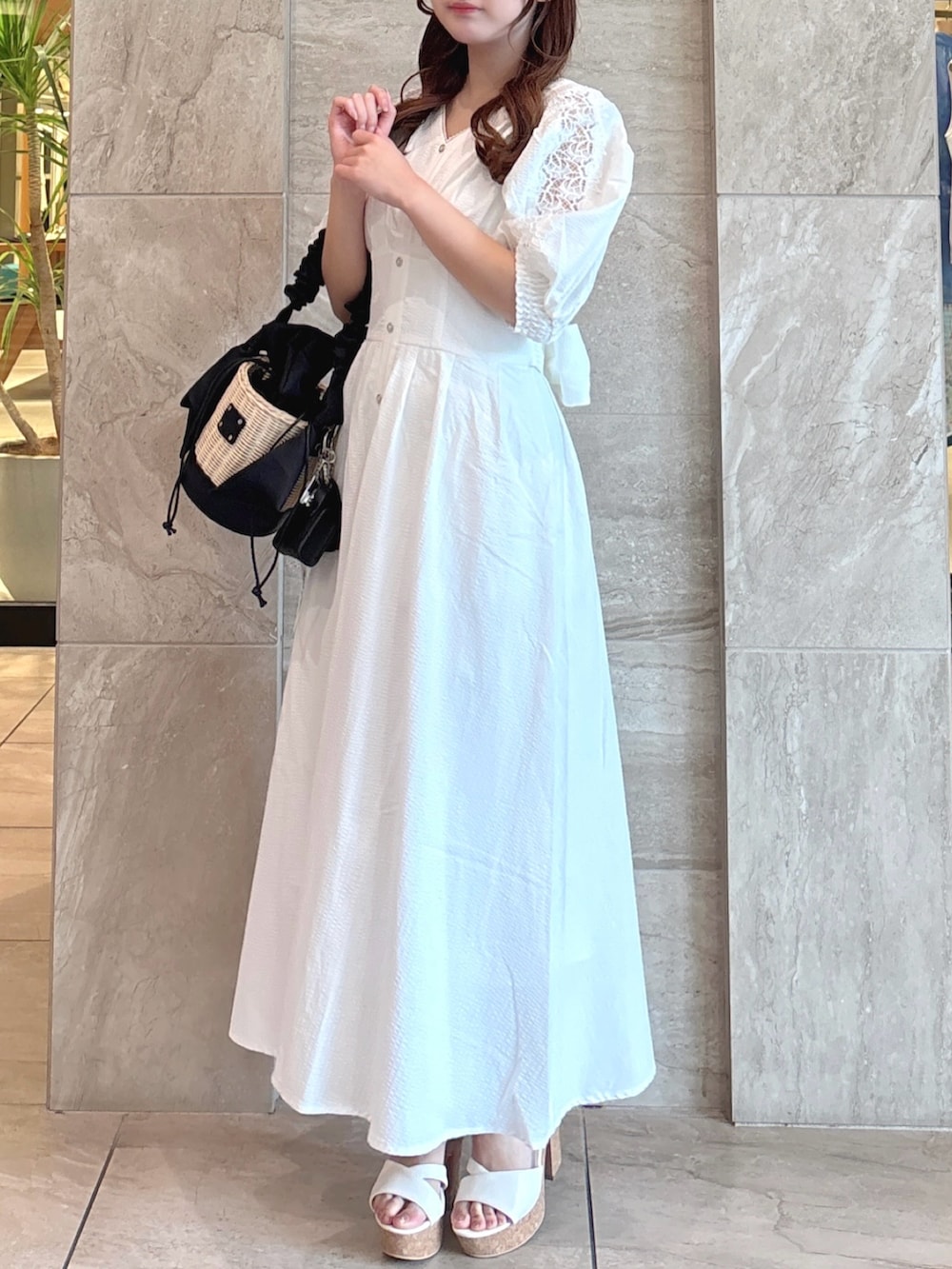 ホワイト系のワンピース、ブラック系のかごバッグ、ホワイト系のサンダルを着用したレディースの夏コーディネートの4枚目の写真