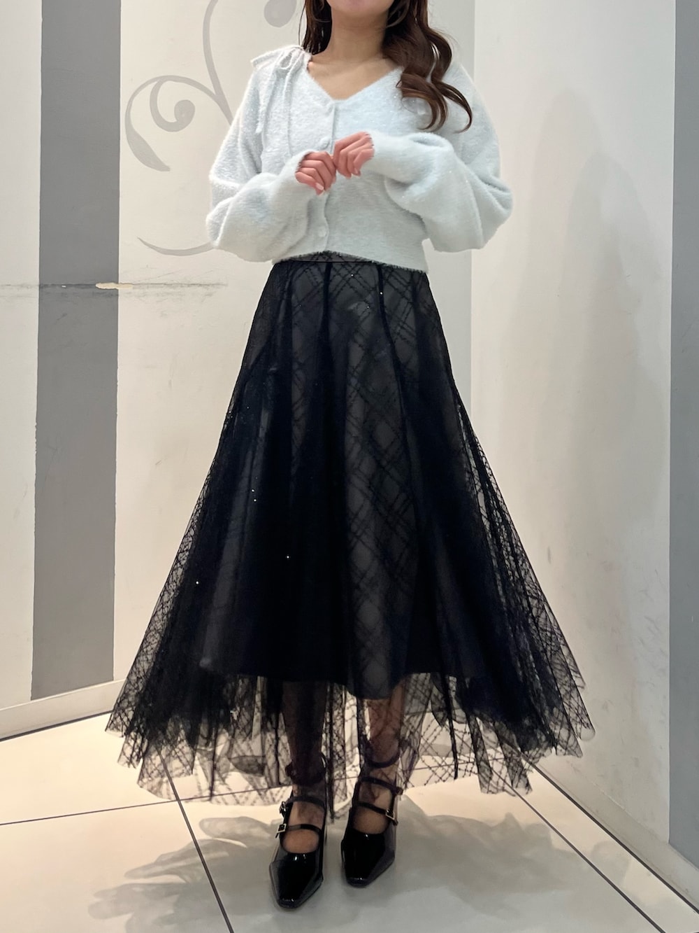 グレー系のカーディガン/ボレロ、グレー系のキャミソール、ブラック系のスカートを着用したレディースの冬コーディネートの2枚目の写真