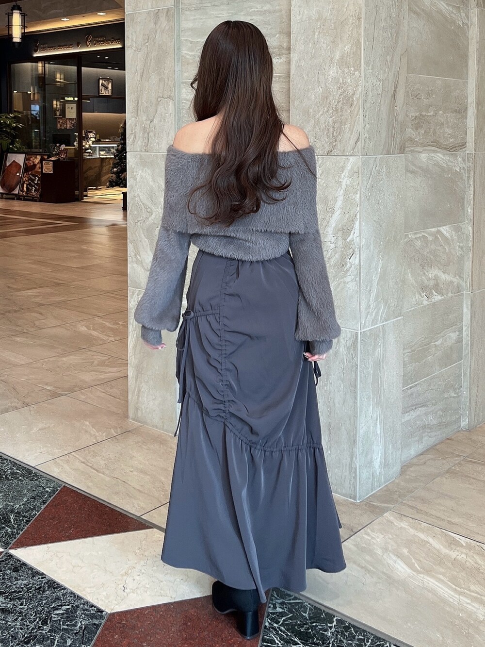 ブラウン系のニット/セーター、グレー系のスカート、その他のブーツを着用したレディースの冬コーディネートの9枚目の写真