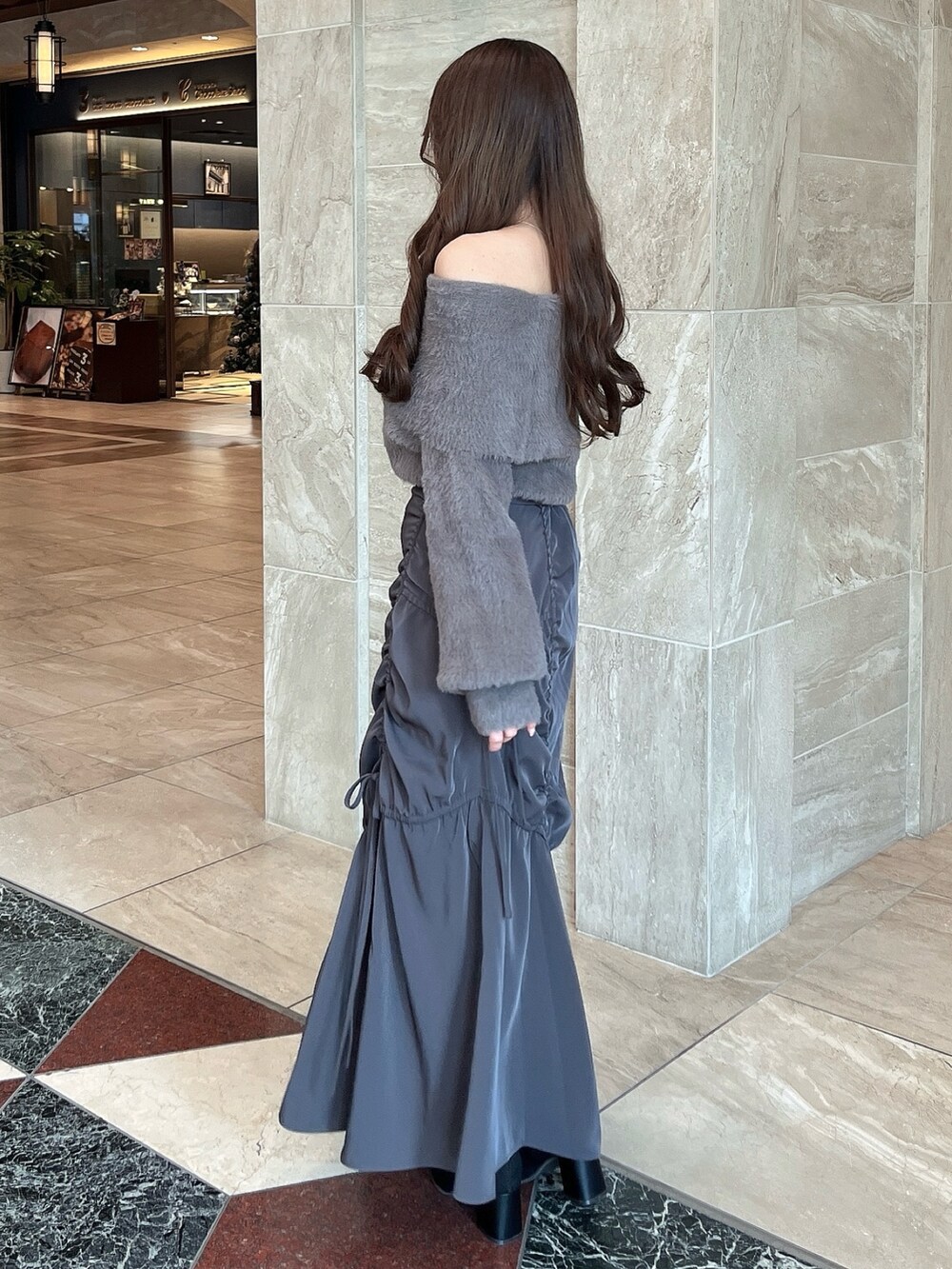 ブラウン系のニット/セーター、グレー系のスカート、その他のブーツを着用したレディースの冬コーディネートの6枚目の写真