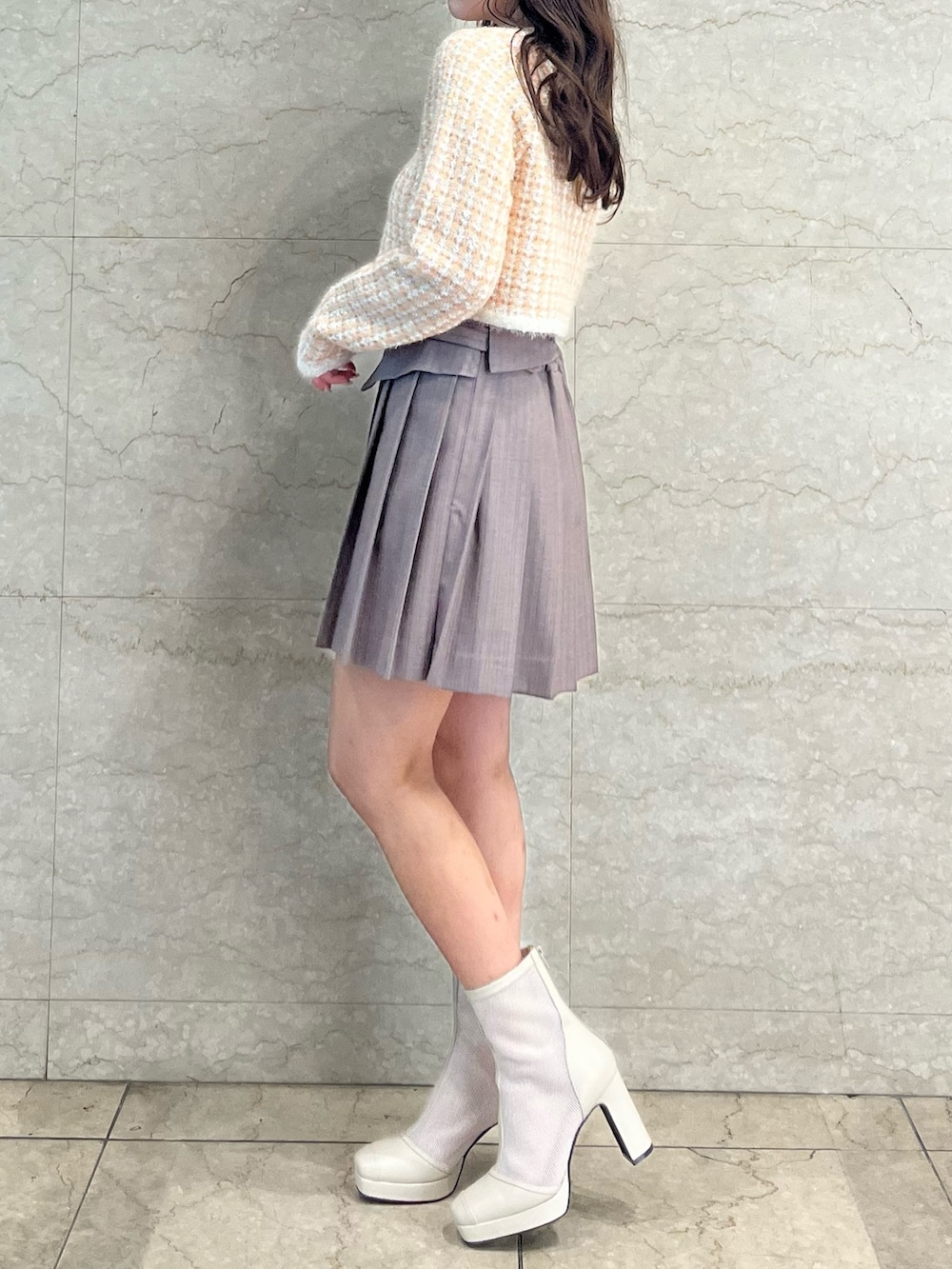 オレンジ系のノーカラージャケット、ベージュ系のスカート、ホワイト系のブーツを着用したレディースの冬コーディネートの3枚目の写真