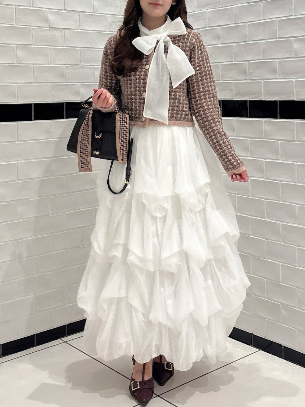 ブラウン系のカーディガン/ボレロ、ホワイト系のシャツ/ブラウス、ブラウン系のショルダーバッグを着用したレディースの秋コーディネートの6枚目の写真