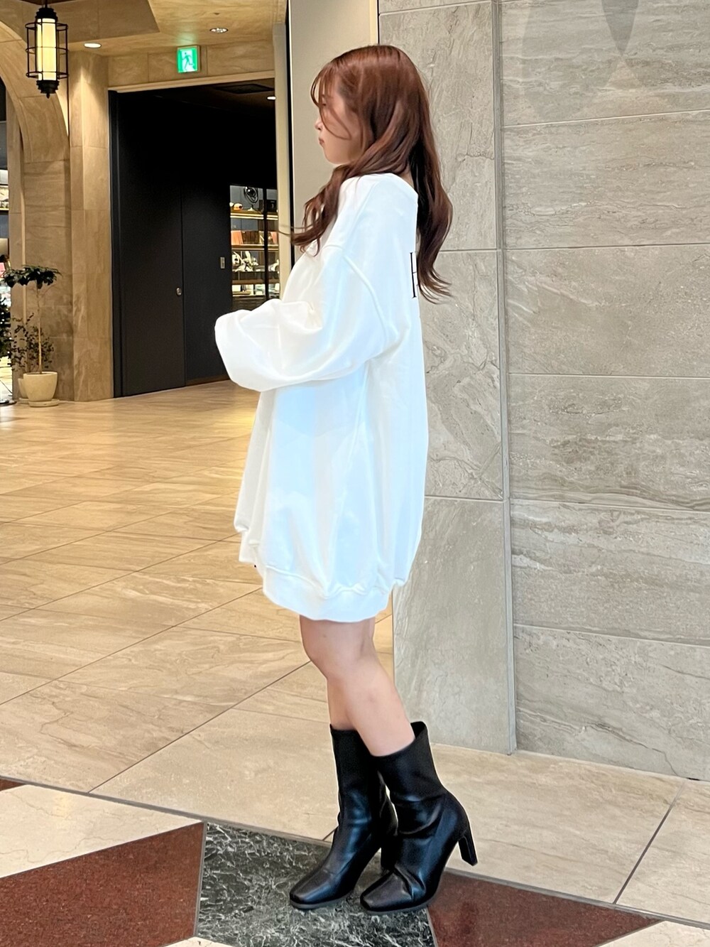 ホワイト系のTシャツ/カットソー、グレー系のスカート、ブラック系のブーツを着用したレディースの冬コーディネートの6枚目の写真