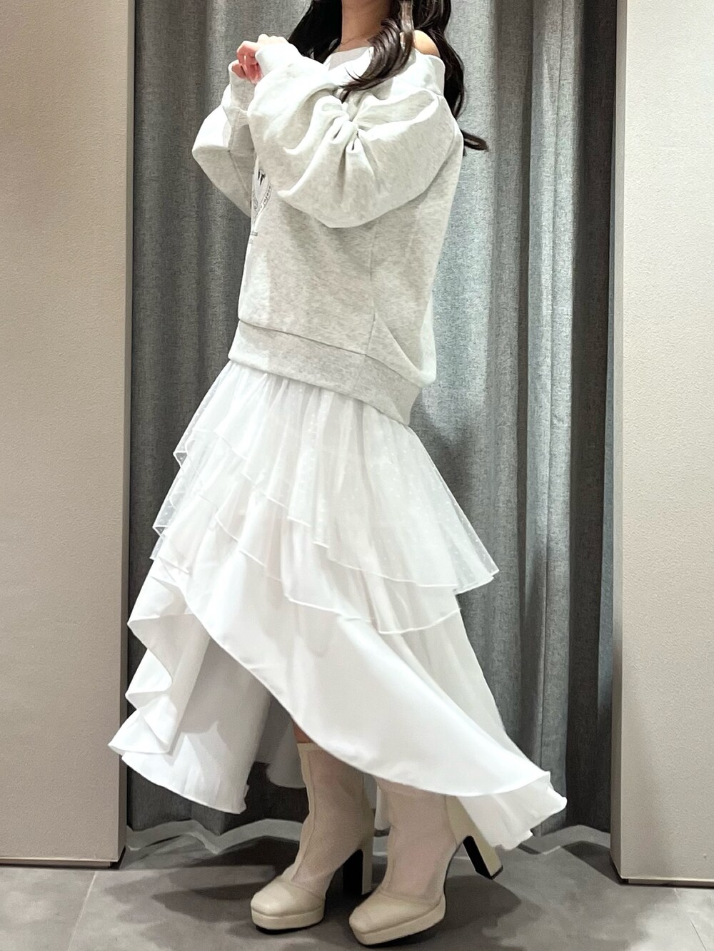 グレー系のスウェット、ホワイト系のスカート、ホワイト系のブーツを着用したレディースの春コーディネートの4枚目の写真