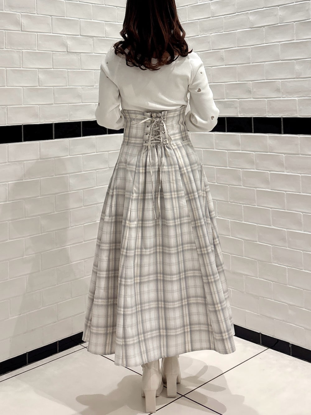 ホワイト系のニット/セーター、ホワイト系のスカート、ホワイト系のブーツを着用したレディースの冬コーディネートの4枚目の写真