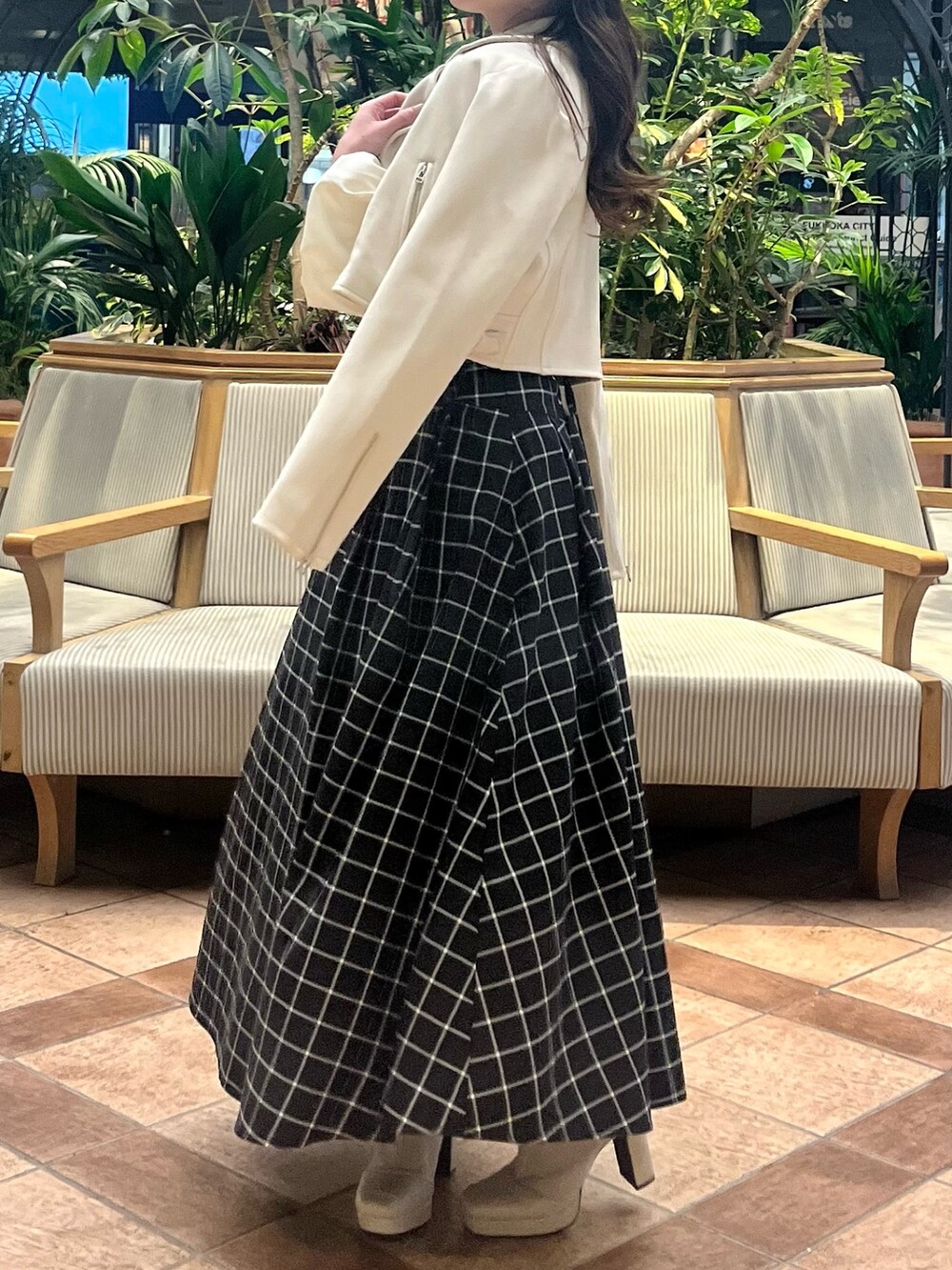 ホワイト系のライダースジャケット、ホワイト系のニット/セーター、ブラック系のスカートを着用したレディースの春コーディネートの6枚目の写真