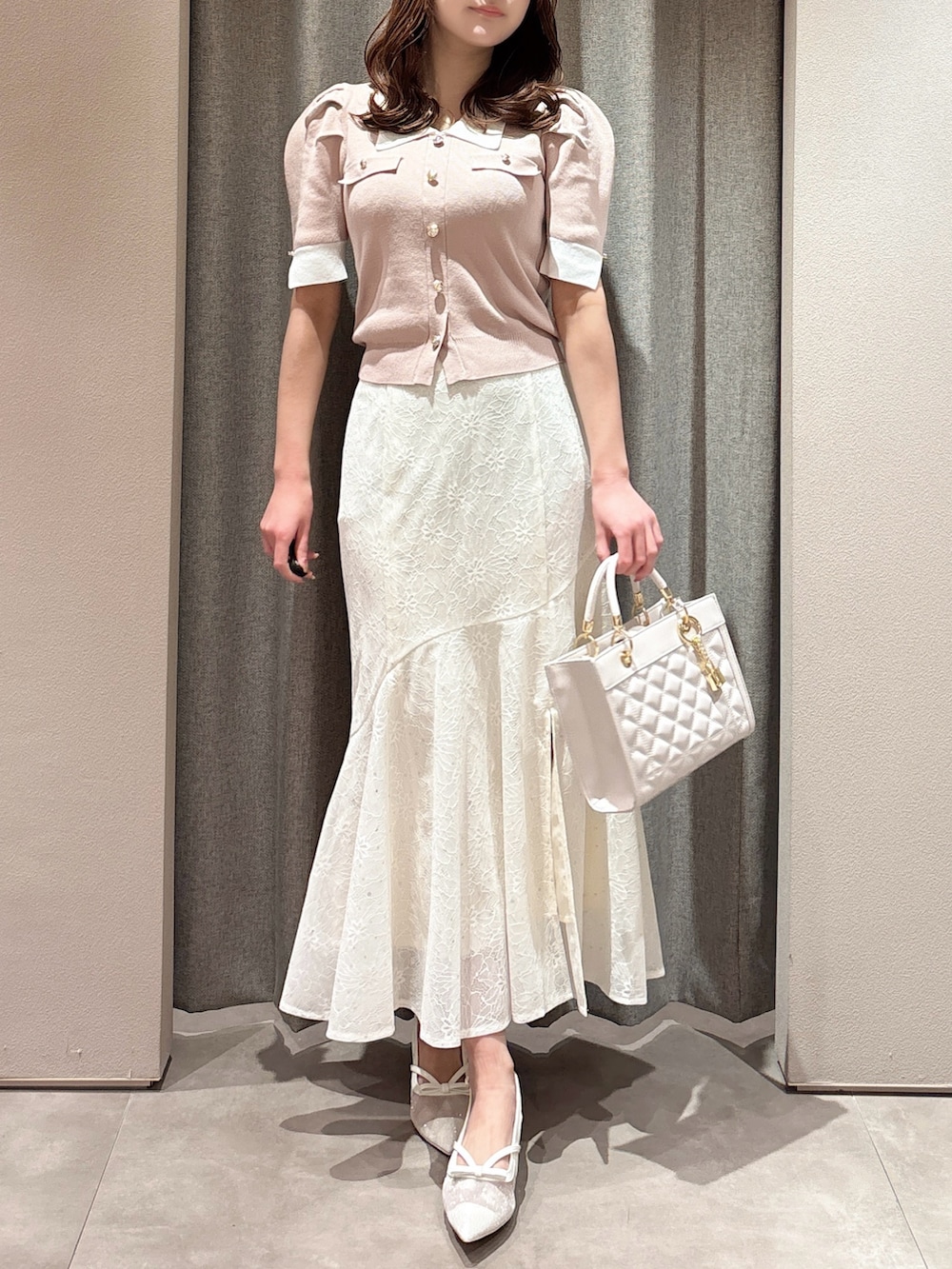 ピンク系のニット/セーター、ピンク系のハンドバッグ、ホワイト系のスカートを着用したレディースの春コーディネートの4枚目の写真