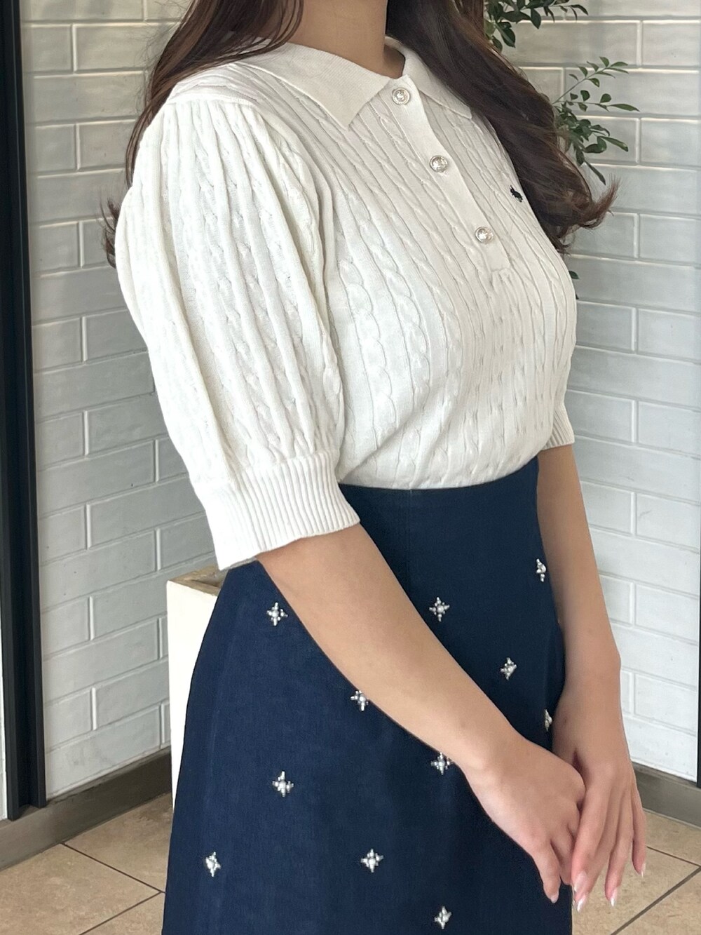 ホワイト系のニット/セーター、ブルー系のデニムスカート、ホワイト系のブーツを着用したレディースの春コーディネートの8枚目の写真