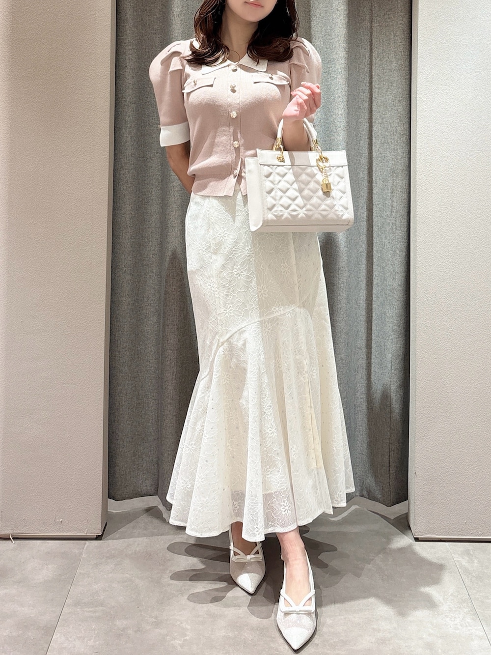 ピンク系のニット/セーター、ピンク系のハンドバッグ、ホワイト系のスカートを着用したレディースの春コーディネートの5枚目の写真