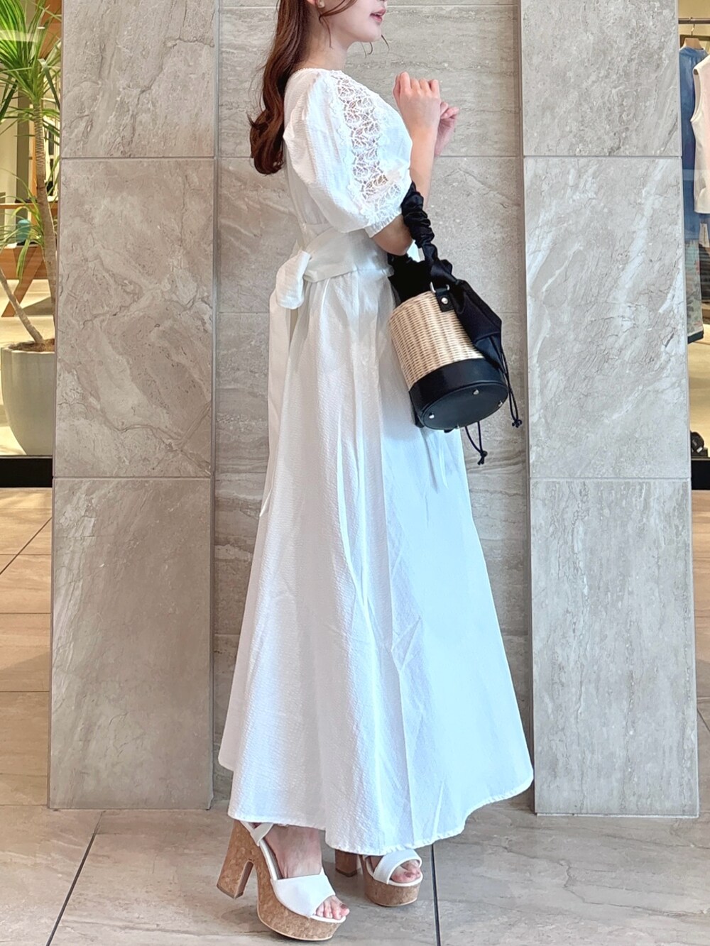 ホワイト系のワンピース、ブラック系のかごバッグ、ホワイト系のサンダルを着用したレディースの夏コーディネートの6枚目の写真