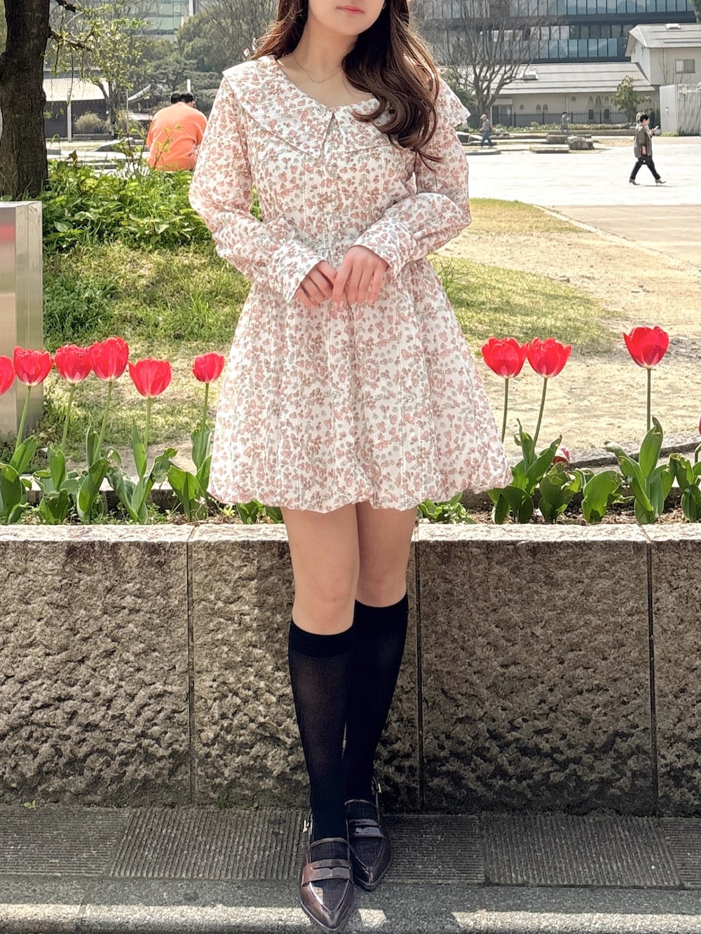 オレンジ系のワンピース、ブラウン系のローファーを着用したレディースの春コーディネートの5枚目の写真