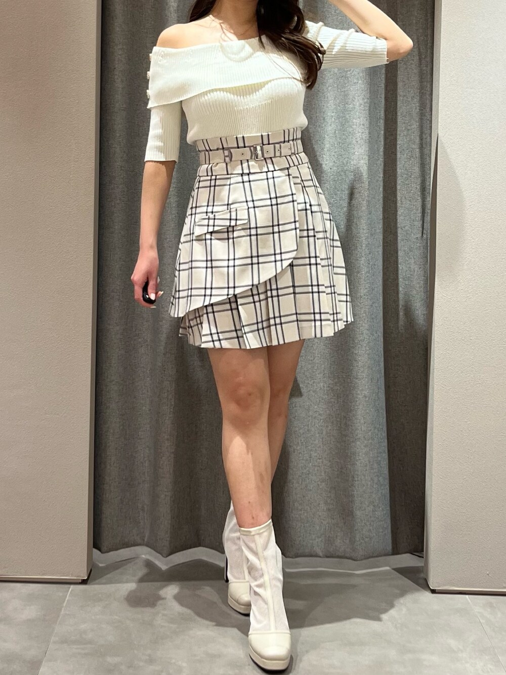 ホワイト系のニット/セーター、ベージュ系のスカート、ホワイト系のブーツを着用したレディースの春コーディネートの2枚目の写真